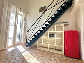 A staircase with a geometric design, a white shelving unit, a red refrigerator, and a window with curtains. - Blu di Ortigia - One Bedroom Apartment, Sleeps 2 (Syracuse)