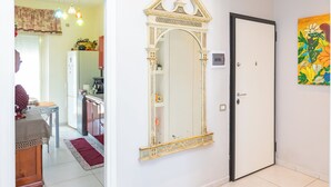 A room with a large ornate mirror, a door, and a colorful painting on the wall. - Poseidone Apartment - Two Bedroom Apartment, Sleeps 4 (Syracuse)