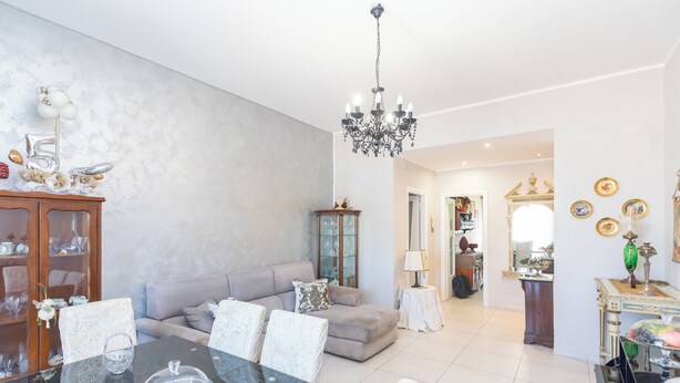 A spacious living room with a dining table, sofa, and chandelier. - Poseidone Apartment - Two Bedroom Apartment, Sleeps 4 (Syracuse)
