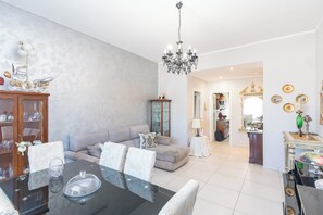Ein geräumiges Wohnzimmer mit Esstisch, Sofa und einer Kronleuchter.