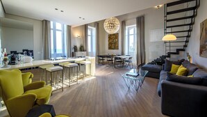 A modern living room with a sofa, yellow chairs, a dining area, and a kitchen. - Lucea Sea Terrace by Ortigiapartments (Syracuse)