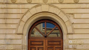 A double wooden door with a semi-circular arch above it, set in a stone building with visible brickwork and a small plaque with the number 4. - Lucea Sea Terrace by Ortigiapartments (Syracuse)