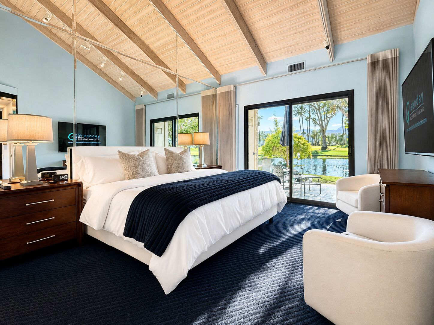 Habitación de hotel con una cama grande, un escritorio, una silla y vistas a una piscina y vegetación.