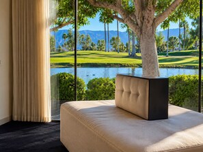 A room with a large window overlooking a golf course and a body of water. - Sunset Serenade: Inspiring Views, Modern Desert Sanctuary...managed by Greenday! (Rancho Mirage)