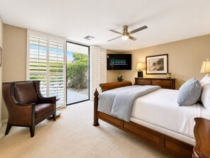 Ein Schlafzimmer mit einem Bett, einem Sessel, einem Fernseher und einem Deckenventilator.
