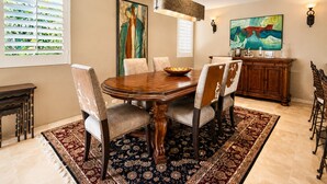 A dining room with a wooden table, six chairs, a chandelier, and artwork on the walls. - Harvard Hideaway: sun-splashed, westerly views in The Springs Country Club. Managed by Greenday! (Rancho Mirage)
