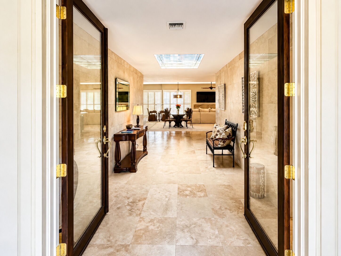 A spacious hallway with a dining area, a sofa, and a decorative bench.