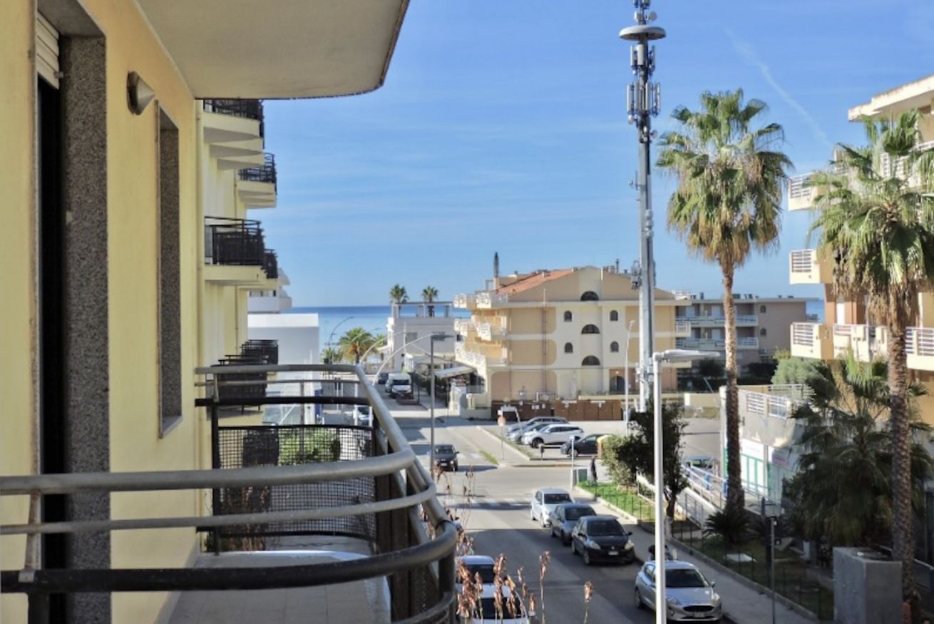 Ein Balkon mit Blick auf eine Straße, Palmen und Gebäude.