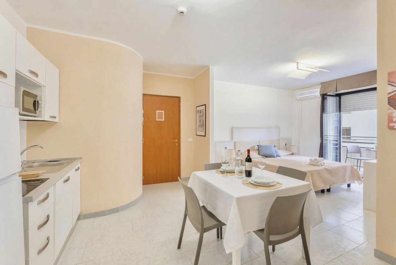 Une chambre d’hôtel compacte dotée d’une kitchenette, d’un coin repas et d’un lit avec balcon.