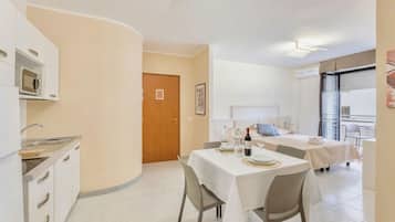 Una camera d'albergo compatta con angolo cottura, zona pranzo e letto con balcone.