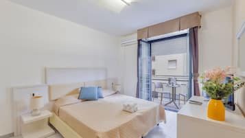 Una camera d'albergo con un letto, un comodino, una lampada e vista sul balcone.