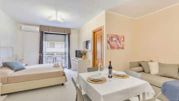 Ein modernes Hotelzimmer mit einem Bett, einem Esstisch für zwei Personen, einer Couch und einem Balkon mit Tisch und Stühlen.