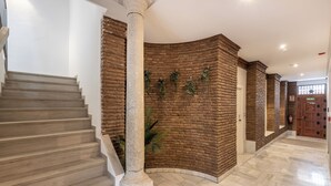A staircase leading to a room with a brick wall and a door labeled "SALIDA". - Apartamentos Realejo Granada Centro 3000 (Granada)