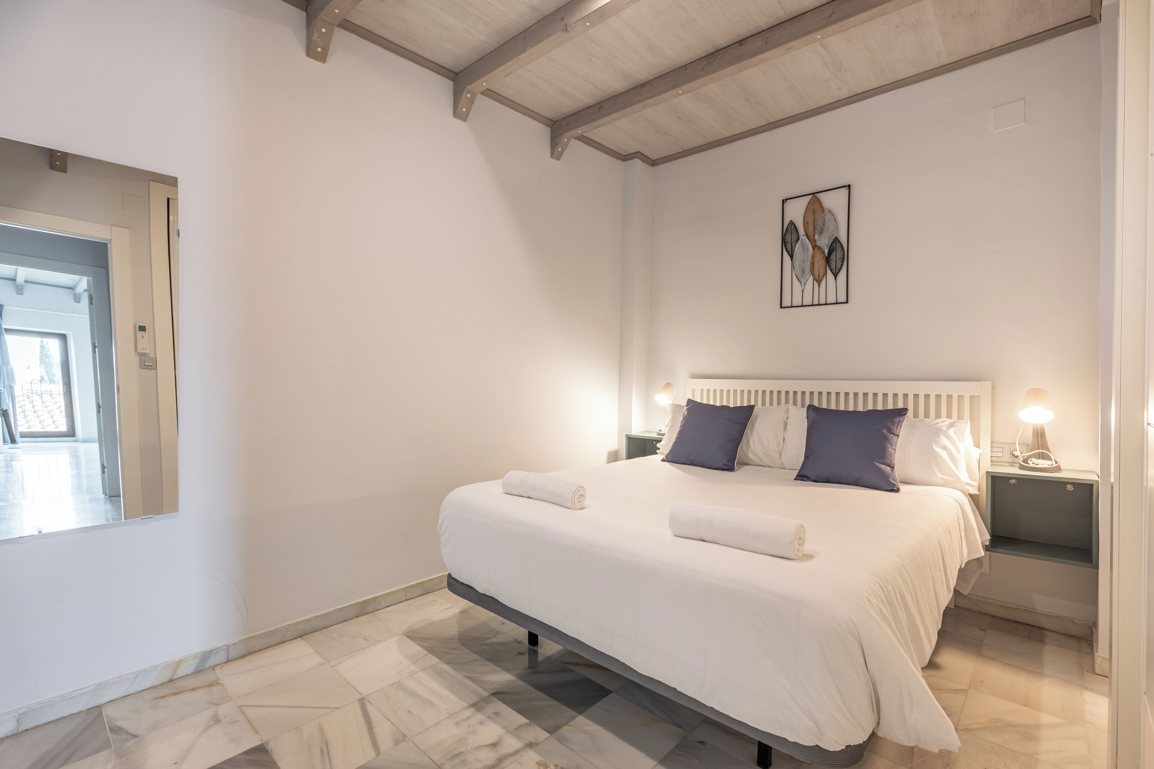 Ein Schlafzimmer mit Bett, Nachttisch, Wandbild und einer Tür.
