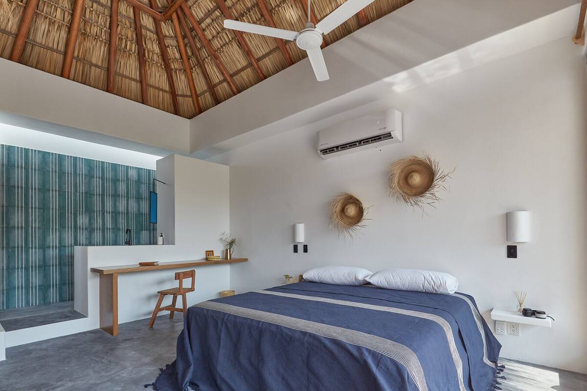 A modern bedroom with a large bed, a desk, and a ceiling fan.
