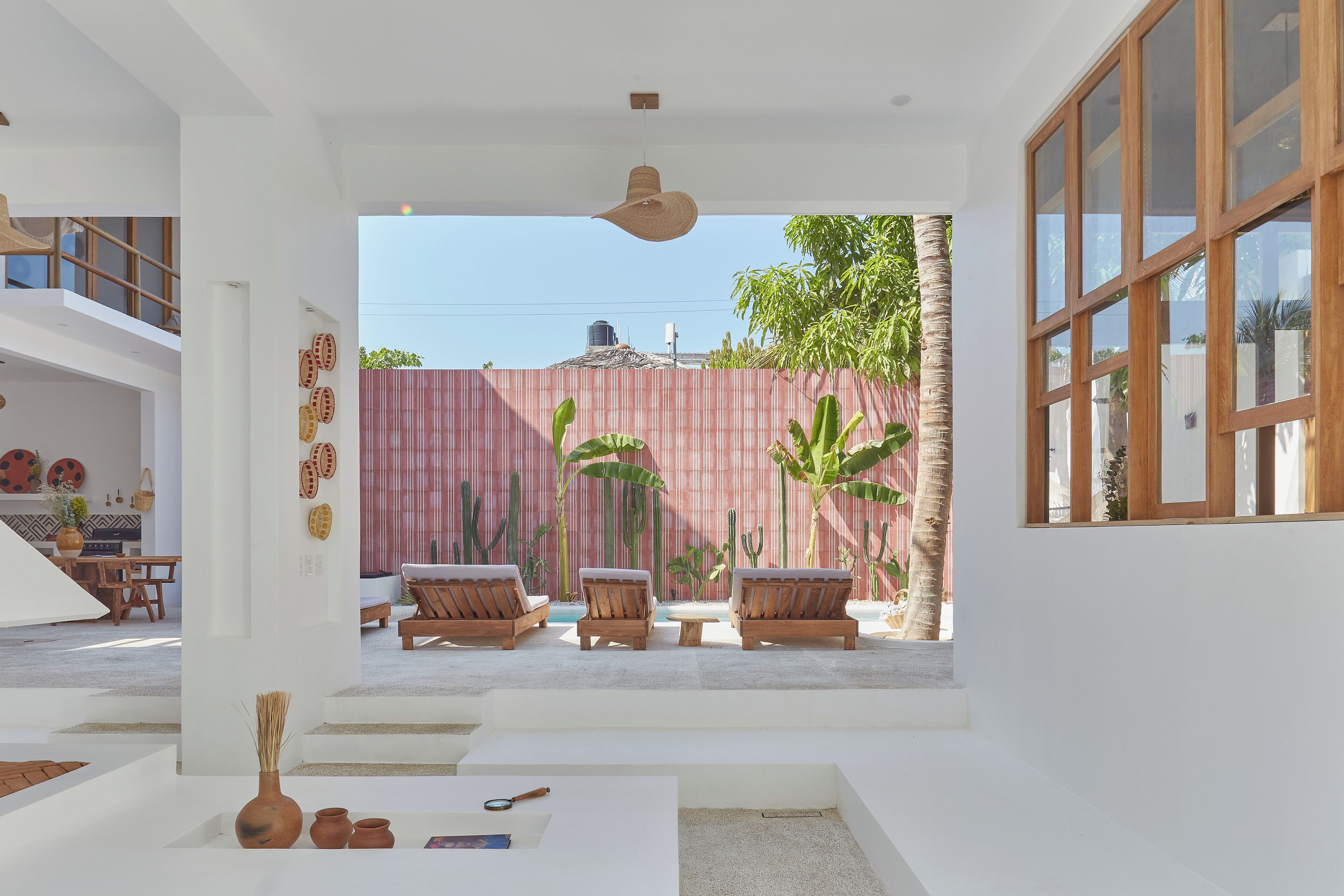 A modern interior with a view of a red fence, wooden furniture, and a ceiling fan.