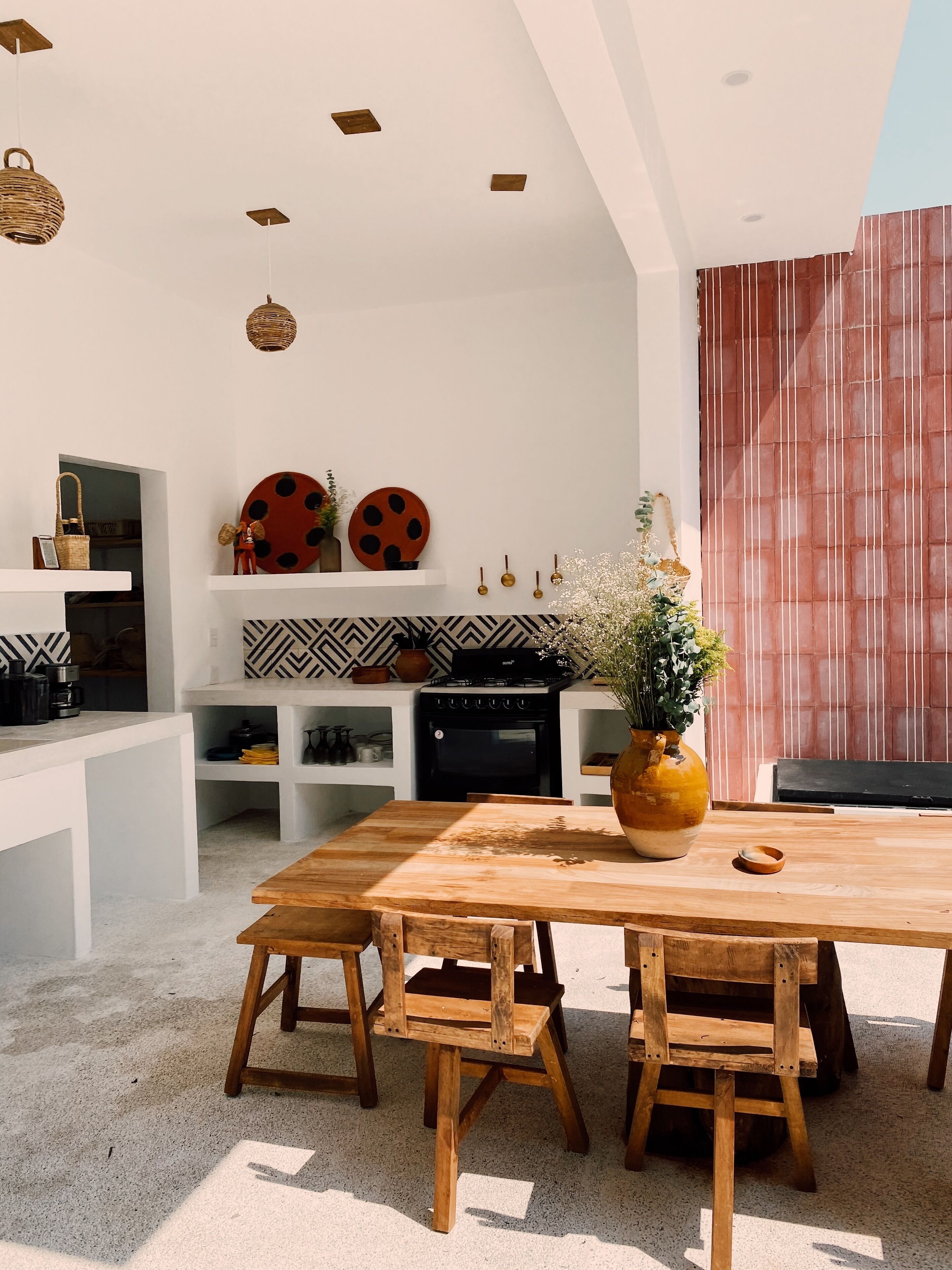 Una cocina moderna con armarios blancos, una mesa de comedor de madera y un jarrón grande con flores.