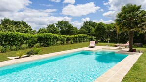 A rectangular swimming pool with a tiled edge, surrounded by a grassy area and trees. - Holiday Home “La Longère Claudine” with Shared Pool, Terrace & Wi-Fi (Fontenet)