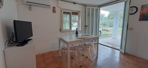 Une petite cuisine avec une table et des chaises, un téléviseur et une fenêtre.