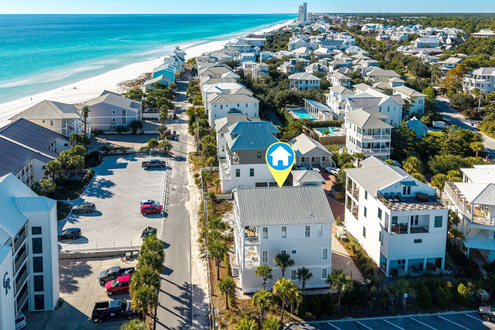 A coastal residential area with houses, a beach, and a parking lot.