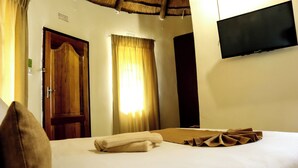 Une chambre d’hôtel avec un lit, un téléviseur à écran plat fixé au mur, une porte en bois et des rideaux.