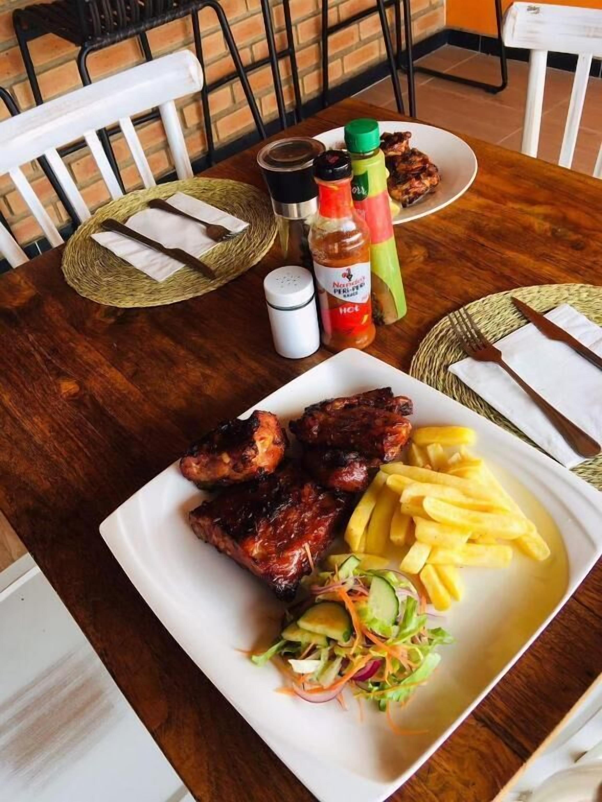 A table set with a plate of grilled meats, French fries, and a side salad.