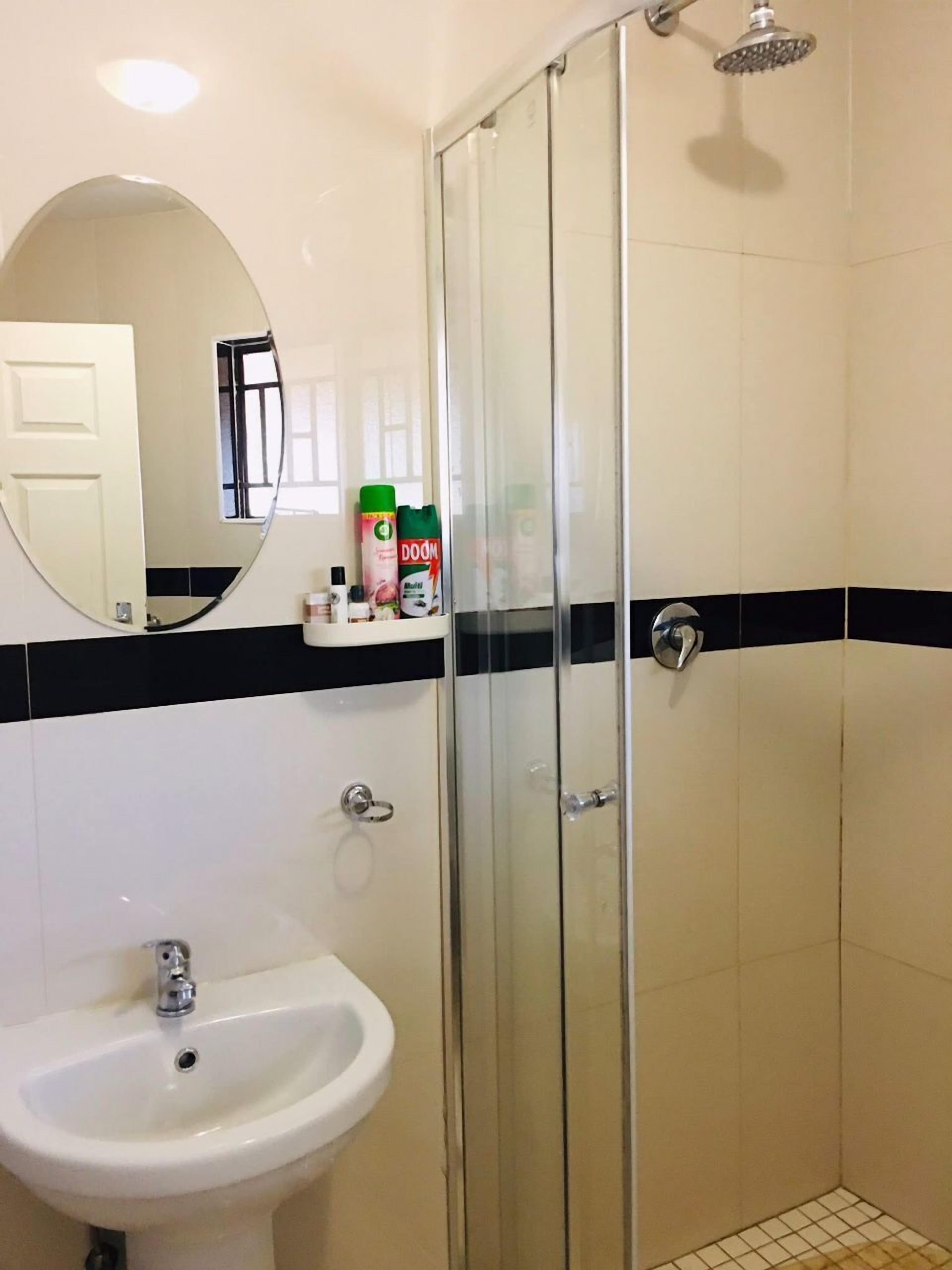 Un baño con cabina de ducha de vidrio, un lavabo blanco y un espejo.