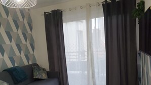 A living room with a sofa, a coffee table, and a view through sheer curtains to an outdoor balcony. - 1 Bedroom unit with balcony in front of Le Bourget Airport (Le Blanc-Mesnil)