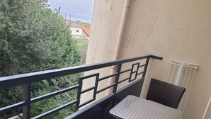 A balcony with a table and two wicker chairs, a metal railing, and a view of greenery and buildings. - 1 Bedroom unit with balcony in front of Le Bourget Airport (Le Blanc-Mesnil)