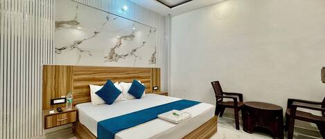 Una habitación de hotel moderna con un cabecero con estampado de mármol, un marco de cama de madera, una colcha azul y un ventilador de techo.
