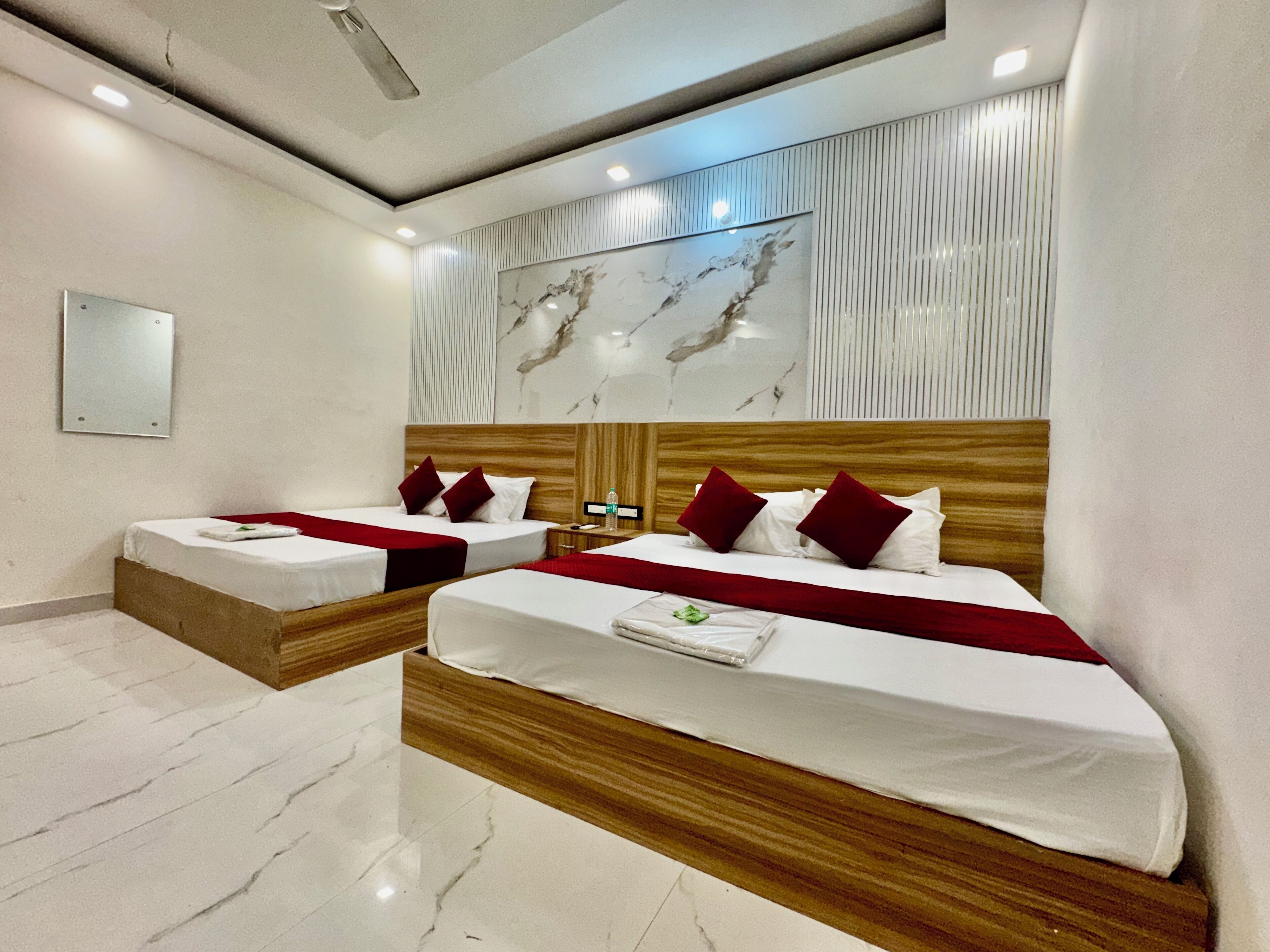 Habitación de hotel con dos camas, suelo de mármol, un espejo grande y una obra de arte de mármol en la pared.