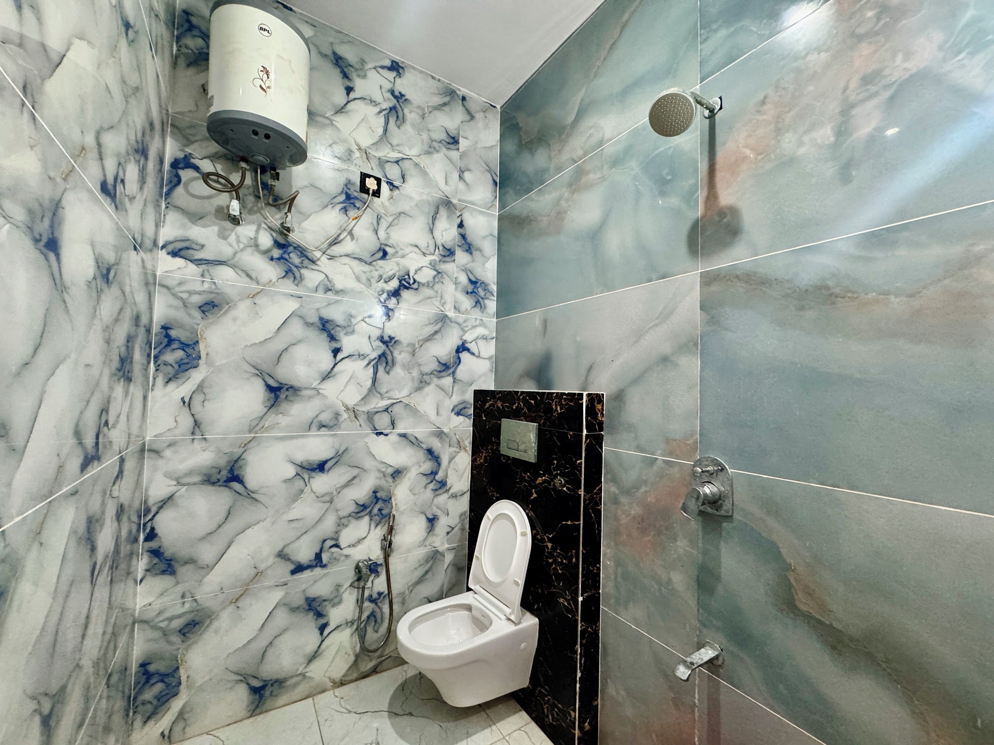 A bathroom with a marble wall, a toilet, a shower, and a hand dryer.