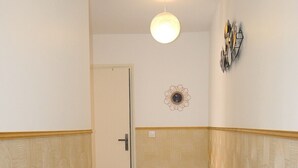 Um corredor com papel de parede estampado, uma porta, um luminário e outro luminário fixado na parede.