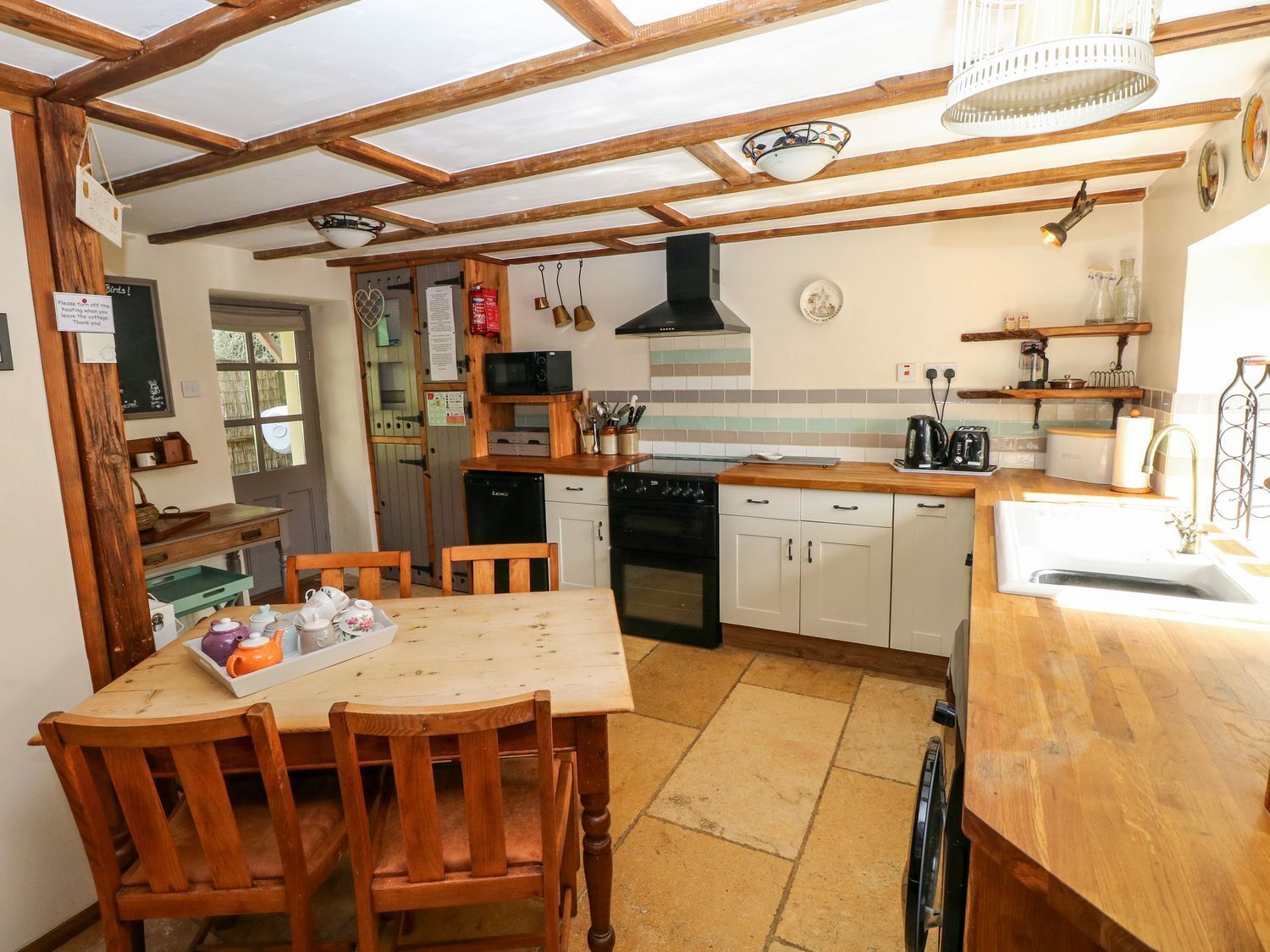 A cozy kitchen with wooden beams, a stove, a microwave, and a sink.