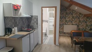 Kompakti keittiö, jossa on ruokailutila, näkyvissä oleva wc ja kuvioitu seinä.