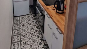 A compact kitchen with white cabinets, a microwave, a refrigerator, a sink, and a wooden countertop. - Le 60 - ODI RENT - In front of Le Bourget AIRPORT (Le Blanc-Mesnil)