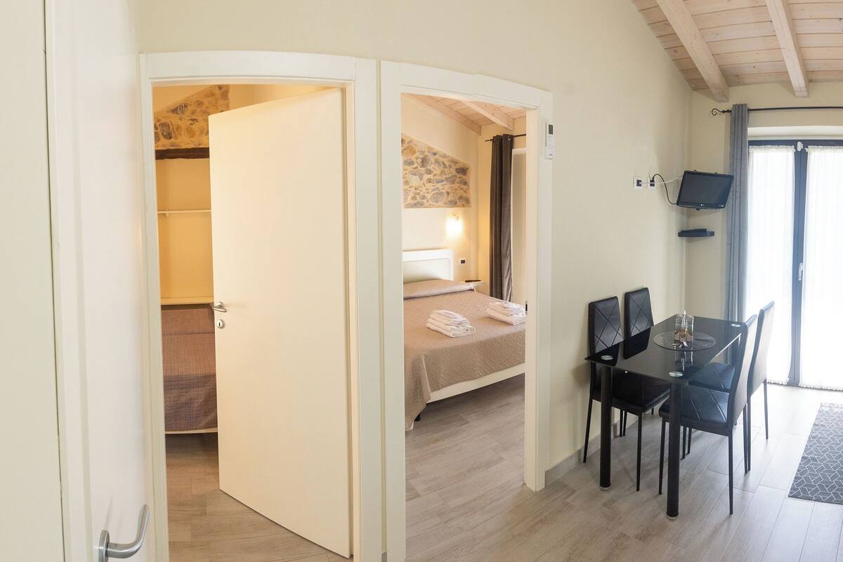 Una habitación de hotel con una cama, un escritorio con sillas y una televisión.
