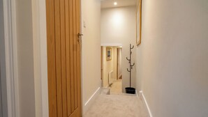A narrow hallway with a wooden door, a coat rack, and a light fixture on the wall. - Modern Plymouth Stay- Near Barbican & City Centre- Ideal for Families / Business (Plymouth)
