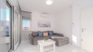 Ein modernes Wohnzimmer mit grauem Sofa, einem weißen Couchtisch und einem Bild an der Wand.
