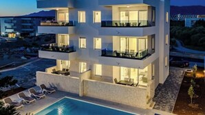 Ein modernes, mehrstöckiges Hotel mit Balkonen, einem Swimmingpool und Blick auf die umliegende Landschaft.