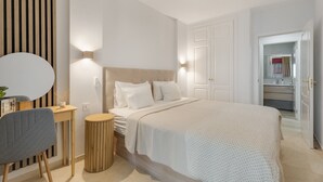 Een slaapkamer met een bed, nachtkastje, stoel en een rond bijzettafeltje.