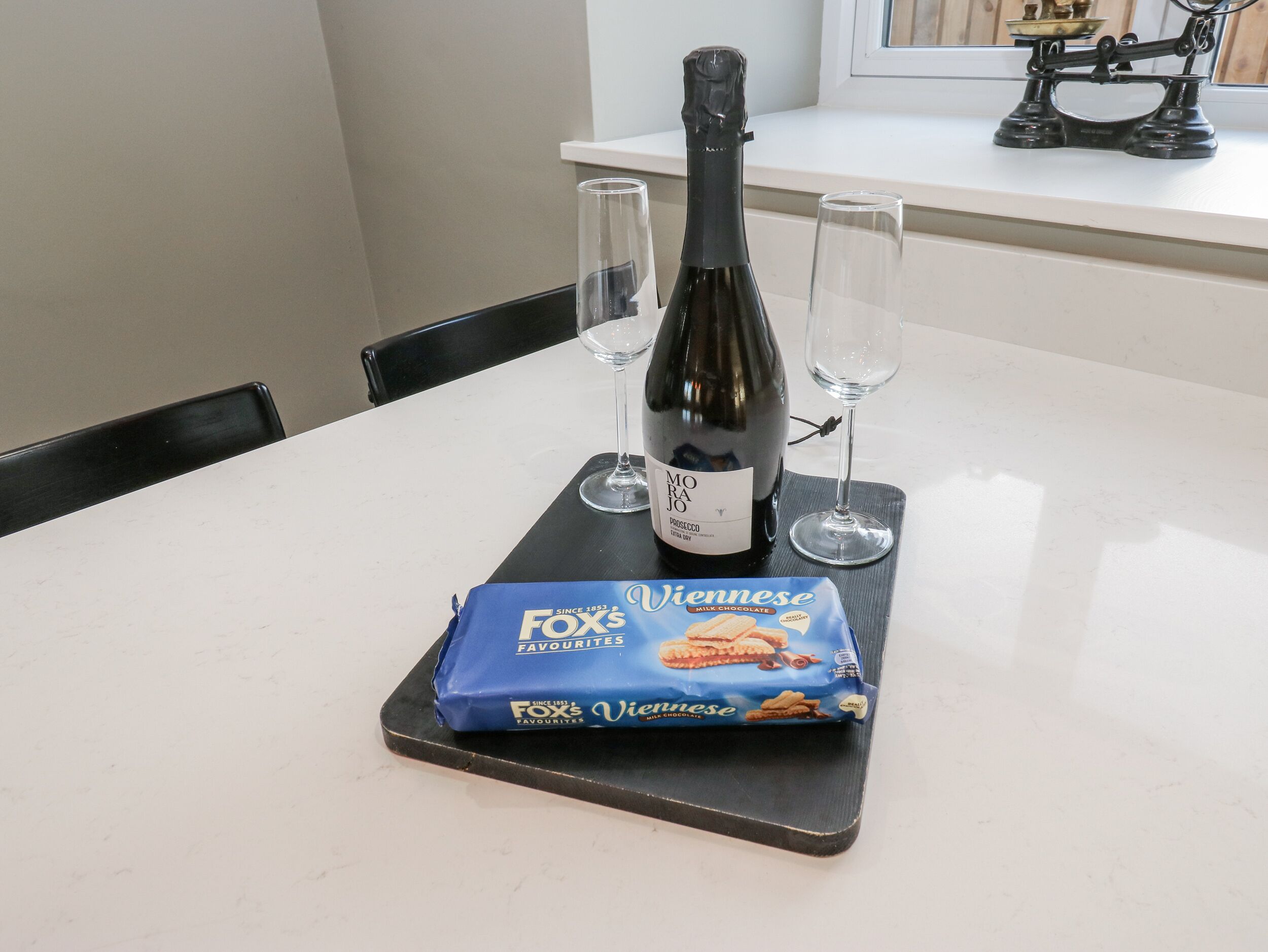 A table with a bottle of Morajio Prosecco, two wine glasses, and a package of Vienna Milk Chocolate.