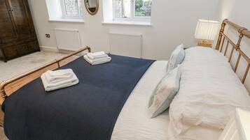 Una camera da letto con un letto, un armadio in legno, un termosifone e due finestre.