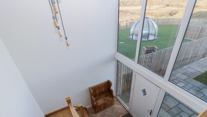 Moderni sisustus, jossa on puinen portaikko, lasiovi, joka johtaa ulos, ja näkymä puutarhaan.