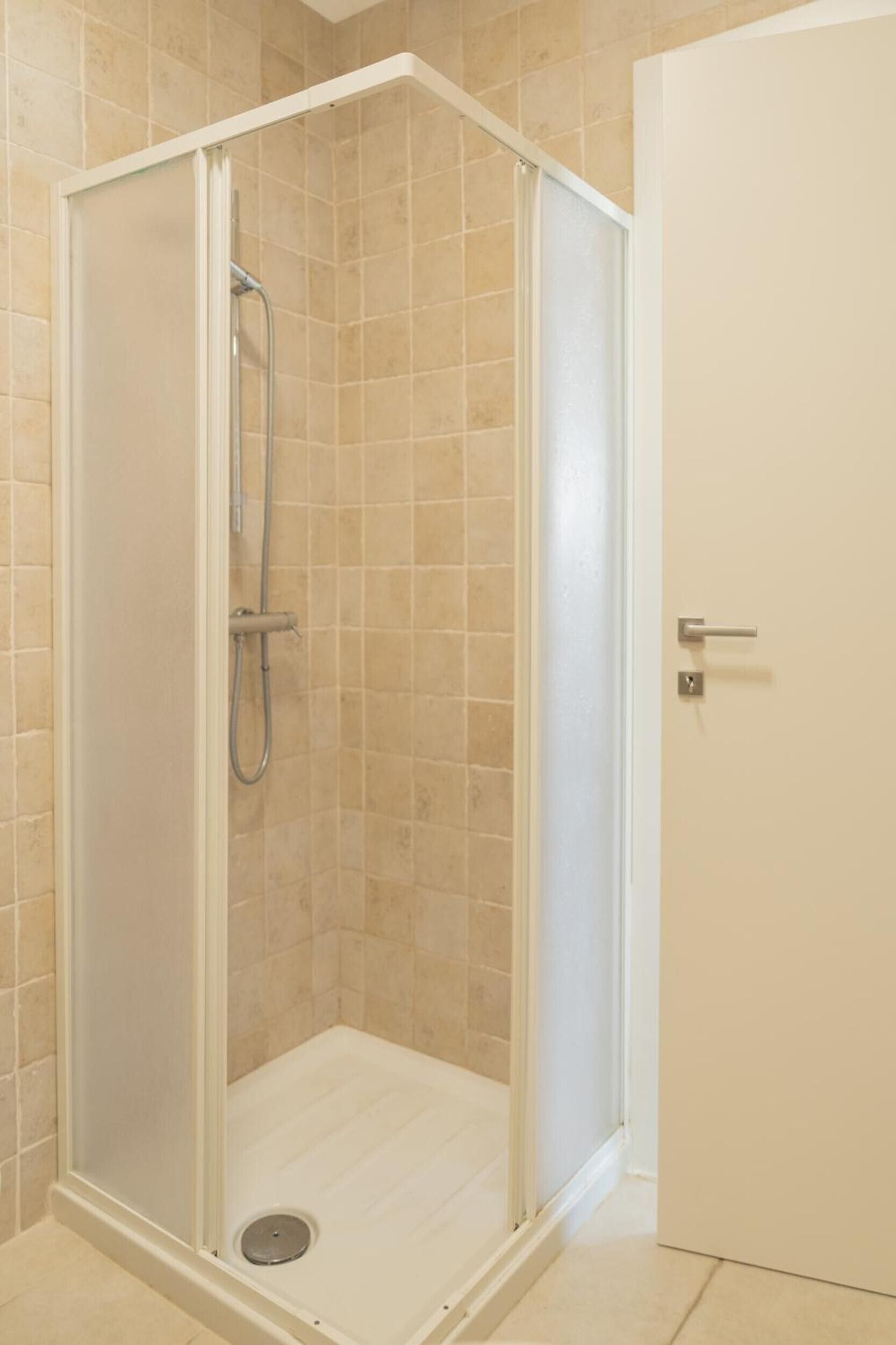 A shower enclosure with a glass door, a showerhead, and a drain.