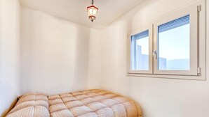 Ein Zimmer mit einem Bett, einem Fenster und einer Pendelleuchte.