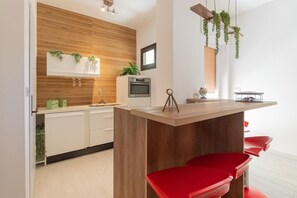 Een koelkast, een oven, een kookplaat, kookgerei, borden en bestek