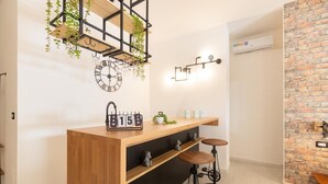 Un espace bar moderne avec un comptoir en bois, deux tabourets, une horloge murale et un calendrier indiquant le « 15 juin ».