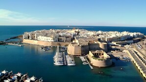Une ville côtière dotée d’une structure fortifiée, d’un port de plaisance avec des bateaux et offrant une vue dégagée sur la mer.