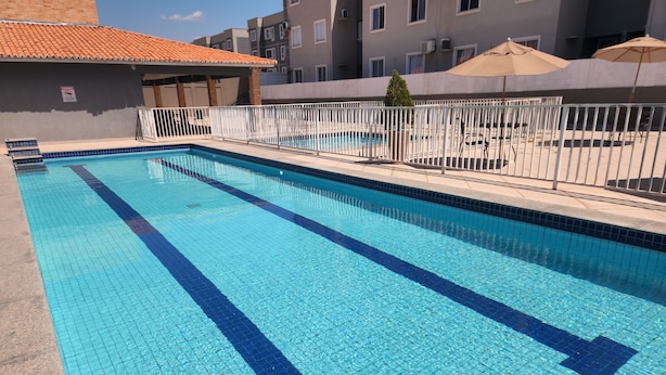 A rectangular swimming pool with blue tiles and a white fence.